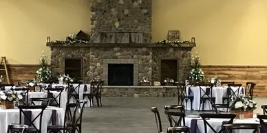 The Stone Hall before the tables are dressed, cross-back chairs set around the hearth
